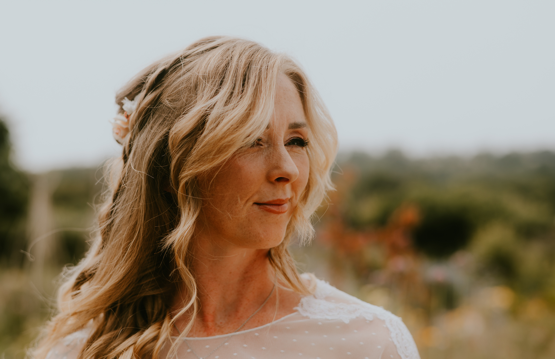 Bride with glowing sun-kissed makeup and loose boho waves in the gardens of River Cottage